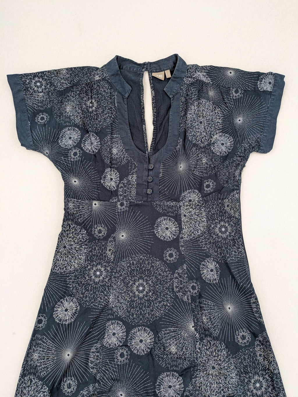 Muster navy dress with white abstract dandelion print, V-neck and collar details.