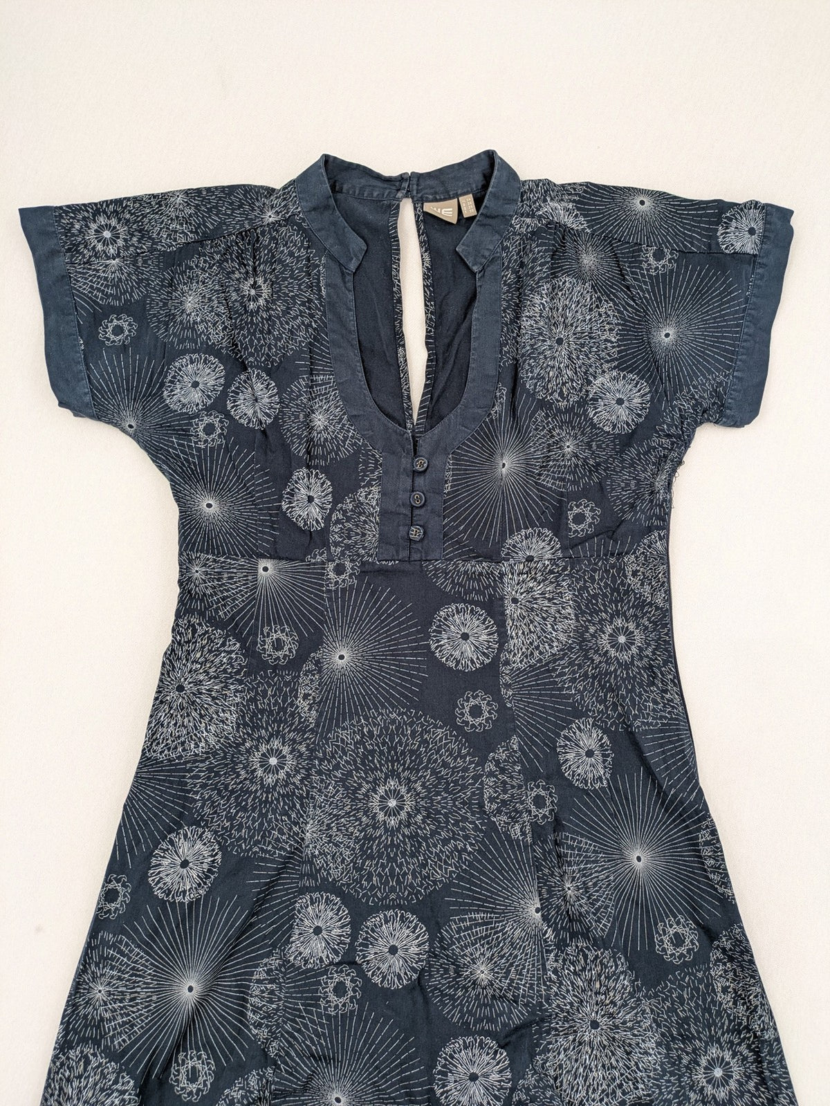 Muster navy dress with white abstract dandelion print, V-neck and collar details.