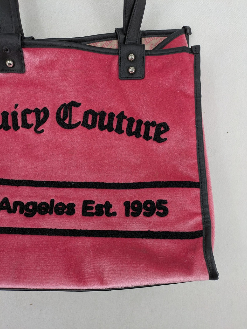Juicy Couture pink velour handbag with oversized black logo and faux leather straps.