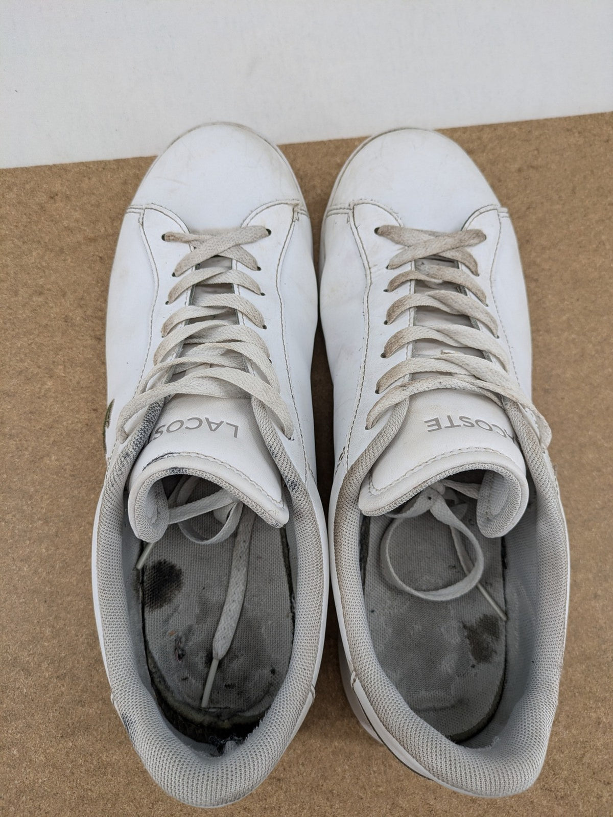 Lacoste cream low top sneakers with iconic crocodile logo and classic design.