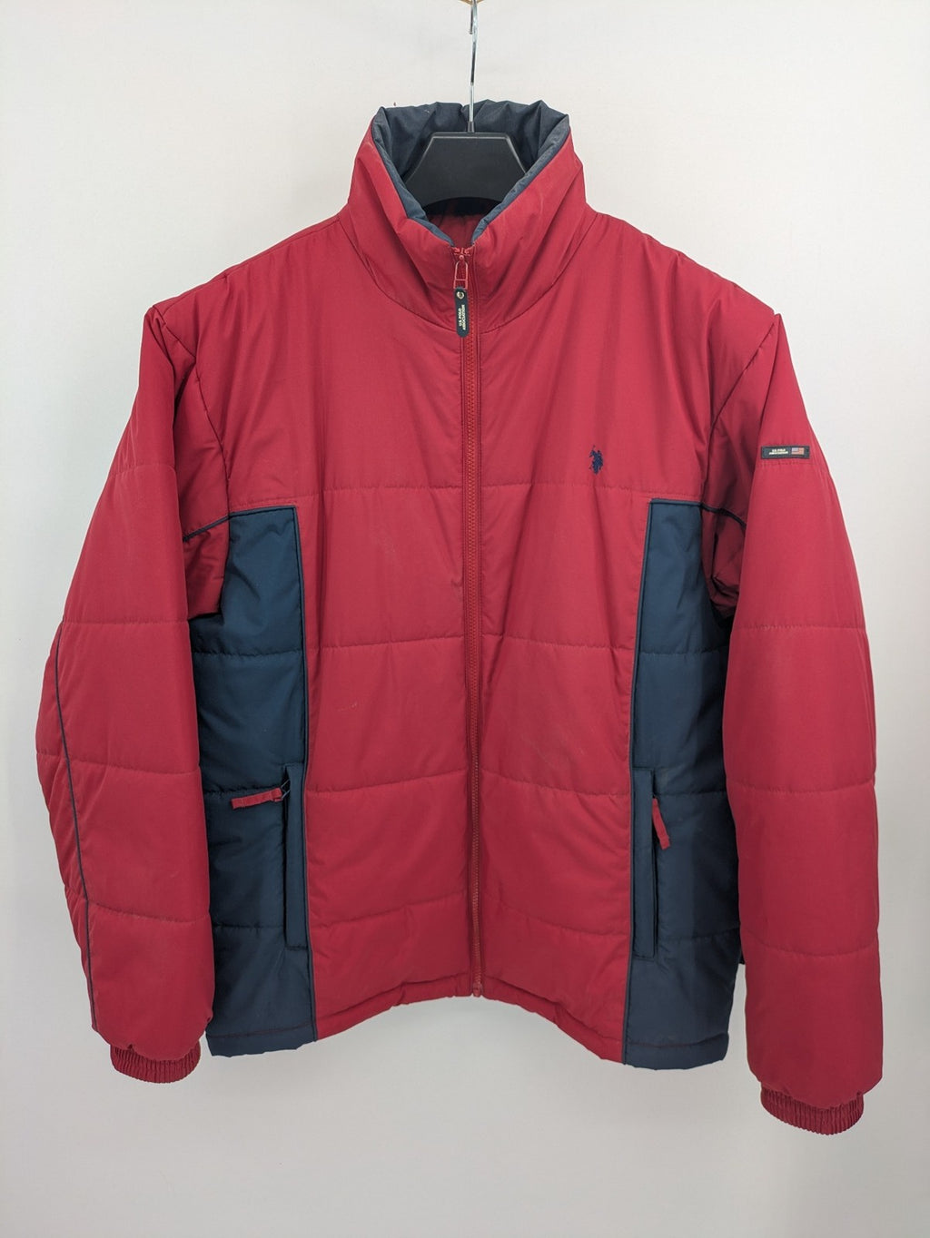 US Polo Assn. puffer jacket navy red two-tone design with embroidered logo and zip pockets.