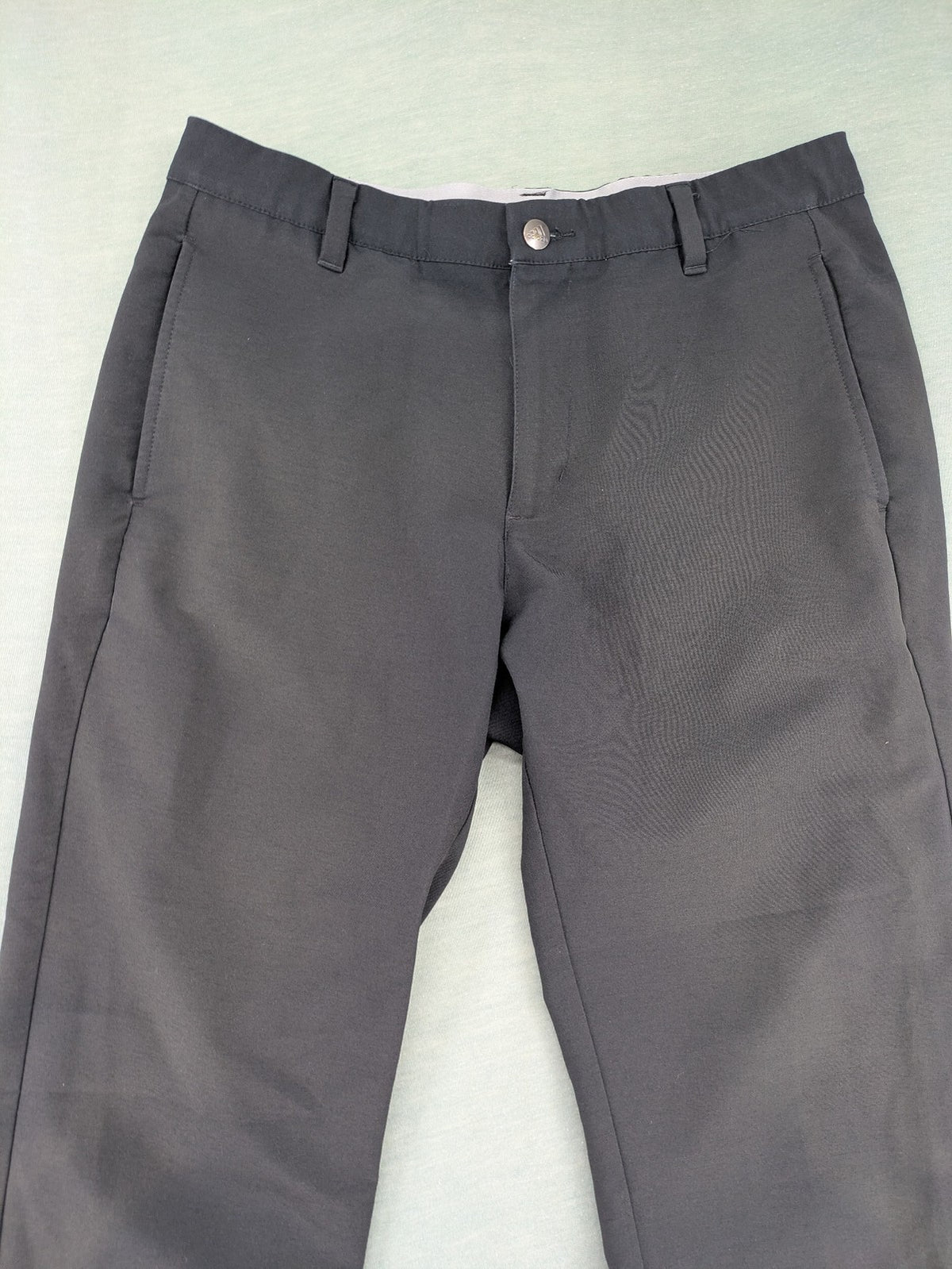 Adidas grey pants with 3-stripe logo, flat-front design, made from performance material.