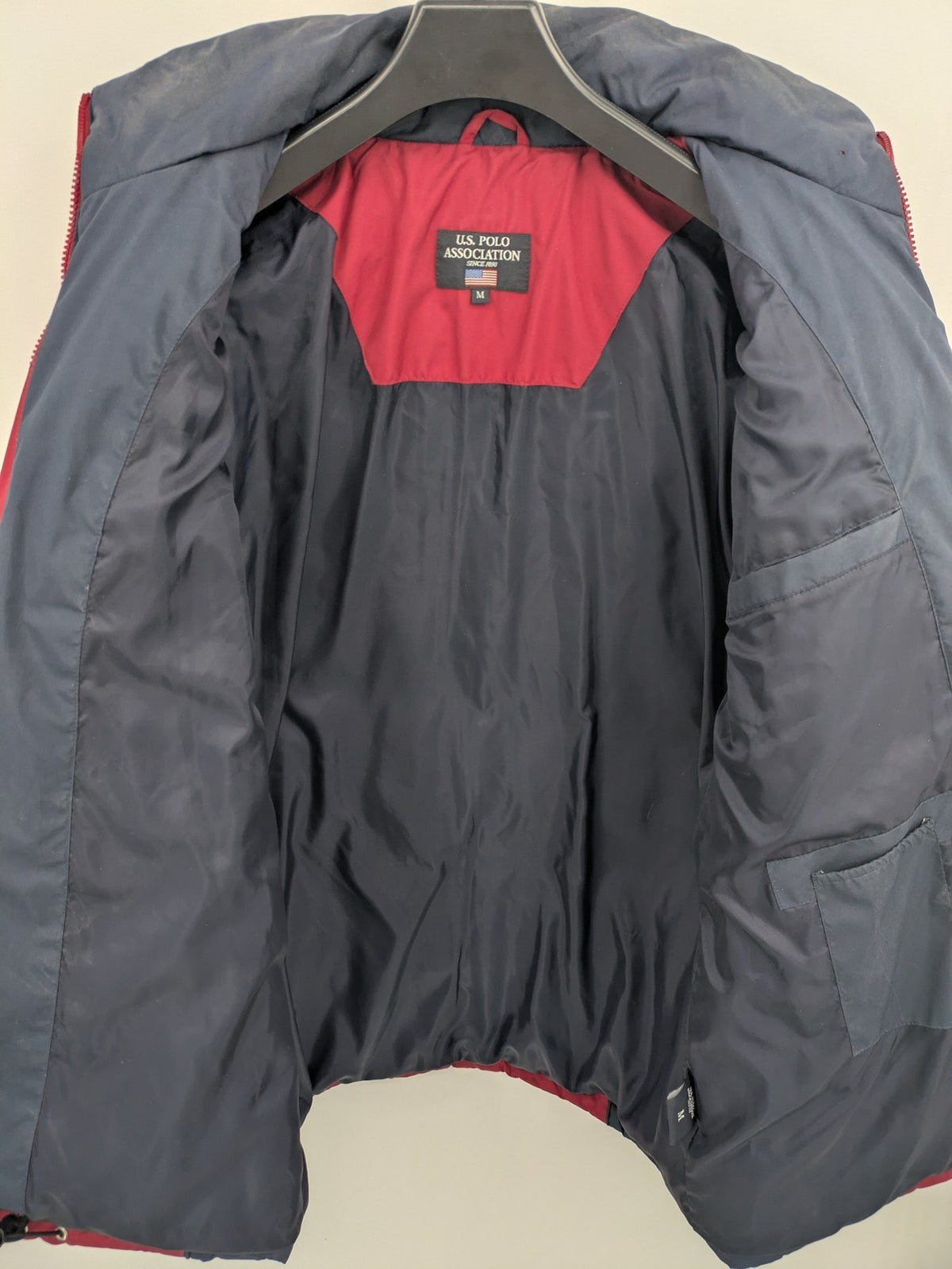 US Polo Assn. puffer jacket navy red two-tone design with embroidered logo and zip pockets.