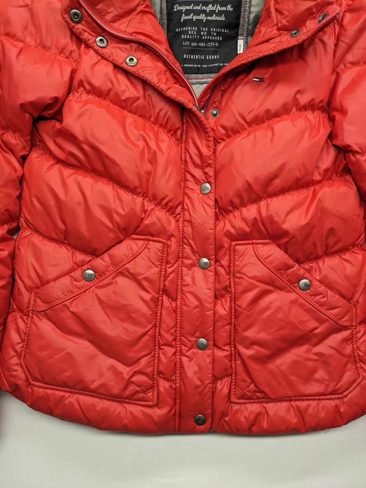 Hilfiger Denim red down jacket with quilted design, stand collar, and zip closure.
