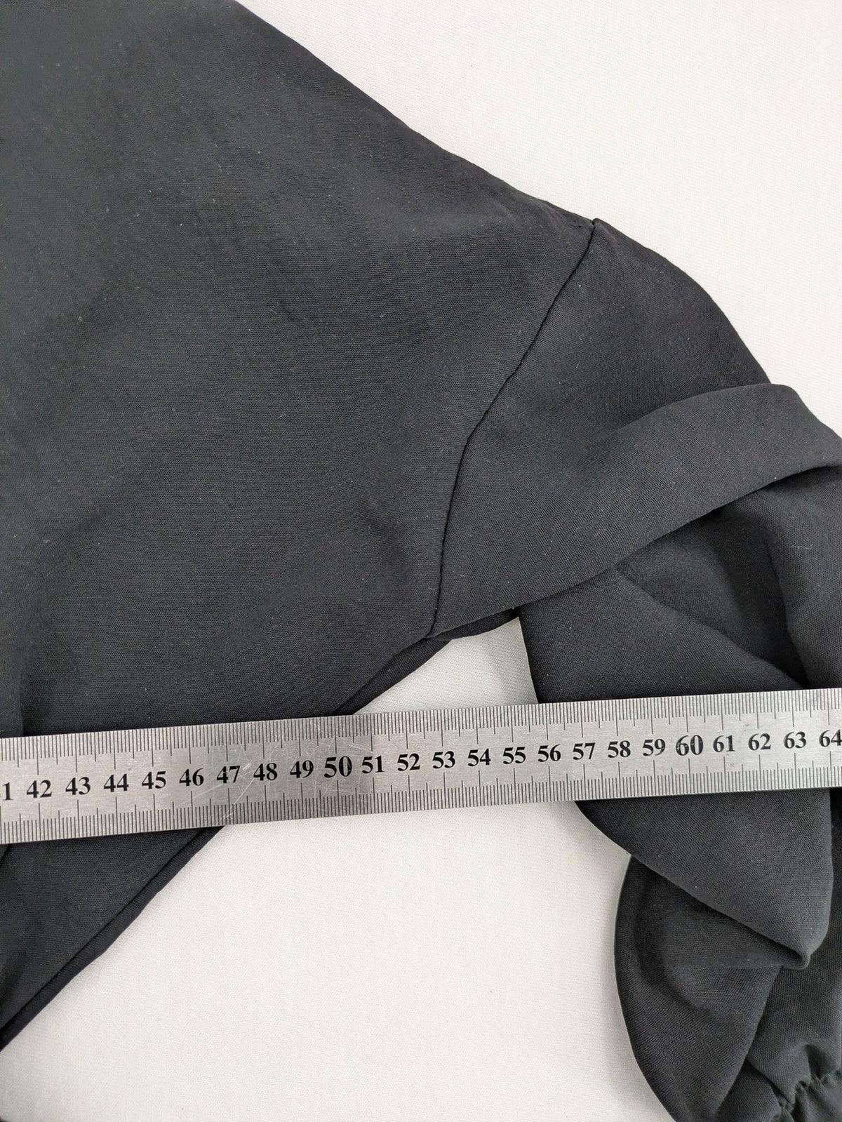Bella black wrap blouse with deep V-neck and ruffled long sleeves.