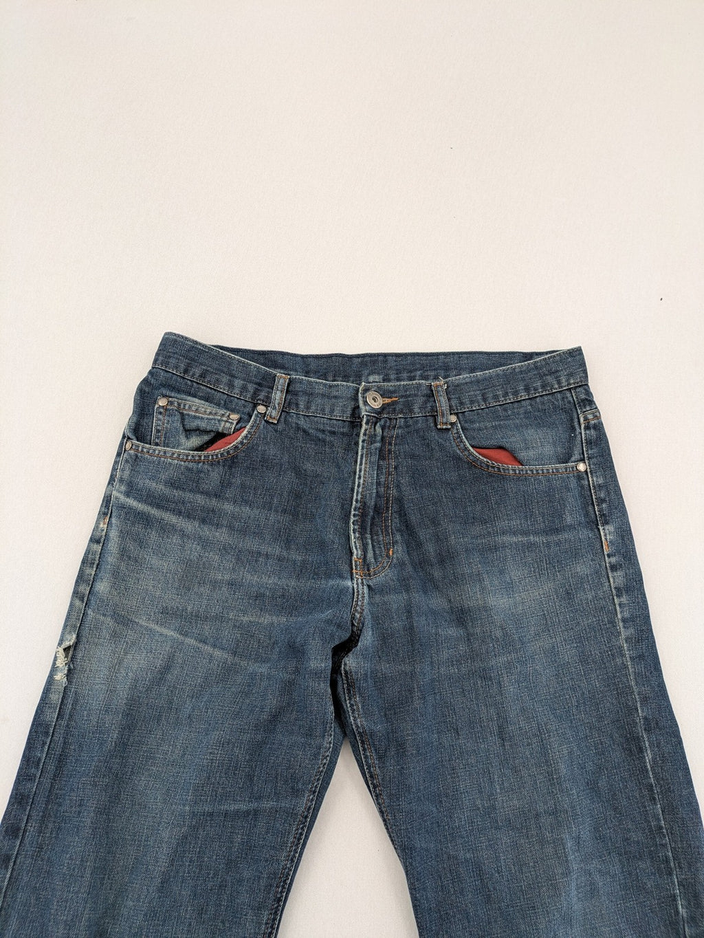 Indygo blue straight jeans 5-pocket style with subtle red pocket detail, cotton material.