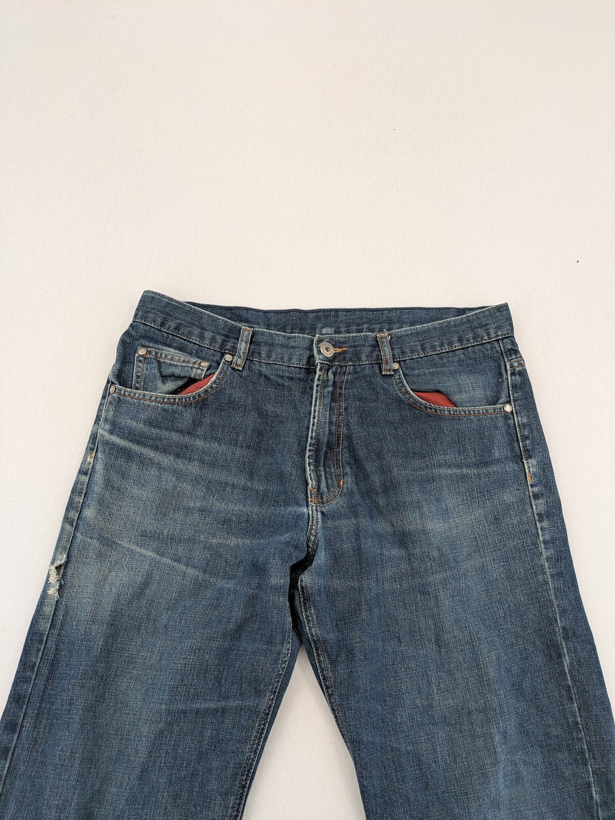 Indygo blue straight jeans 5-pocket style with subtle red pocket detail, cotton material.