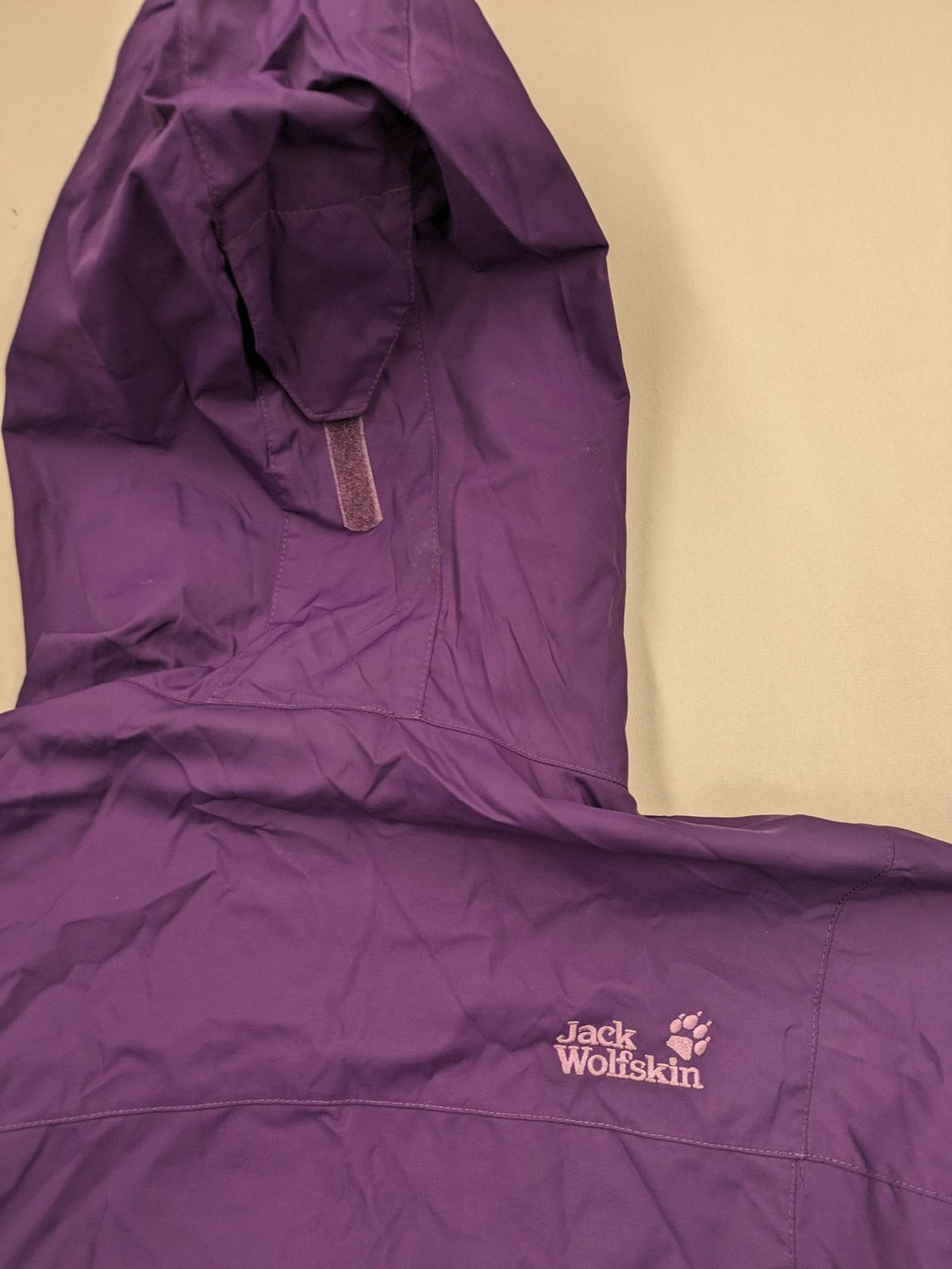 Jack Wolfskin purple outdoor jacket with adjustable hood and full zip, lightweight Stormlock material.