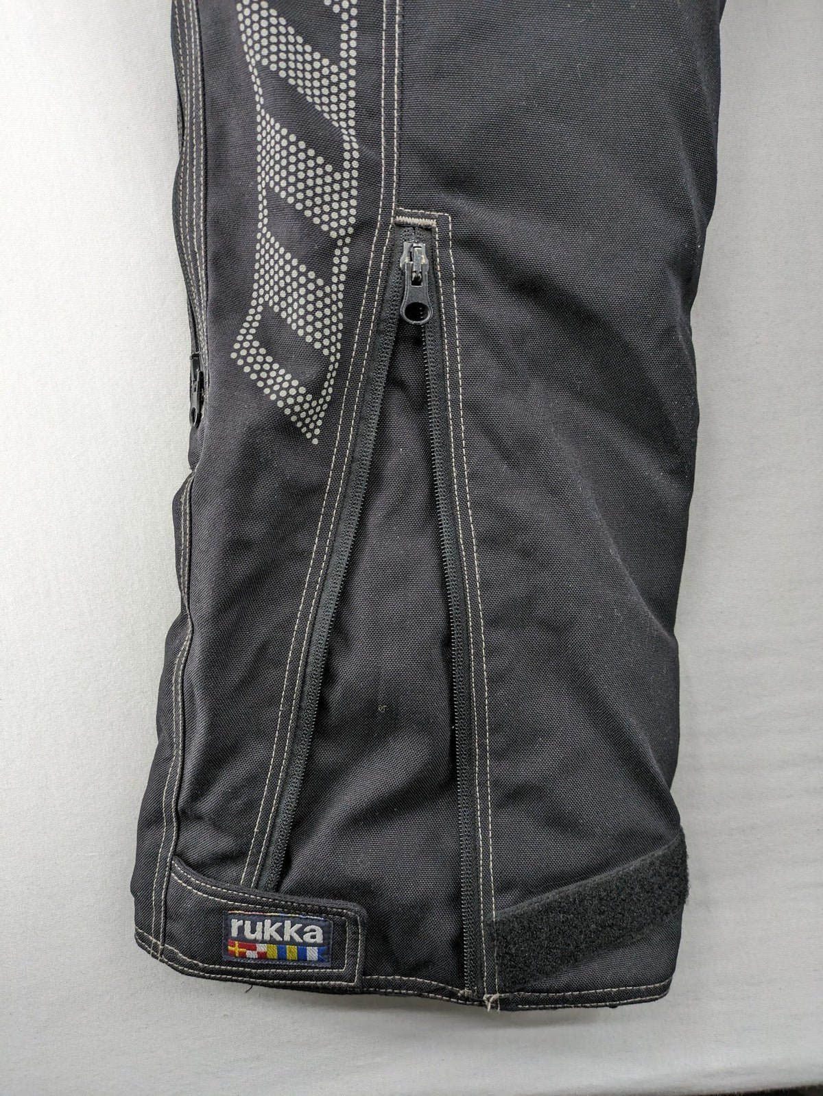 Rukka black motorcycle chaps with grey accents and CE knee protectors, made from durable Cordura.