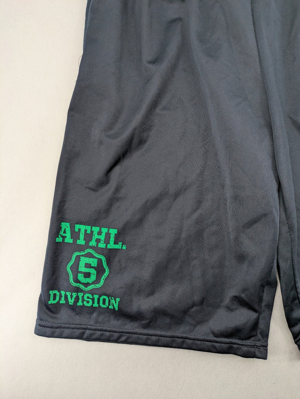 okay grey cargo shorts with green "ATHL. 5 DIVISION" graphic print and side pocket.