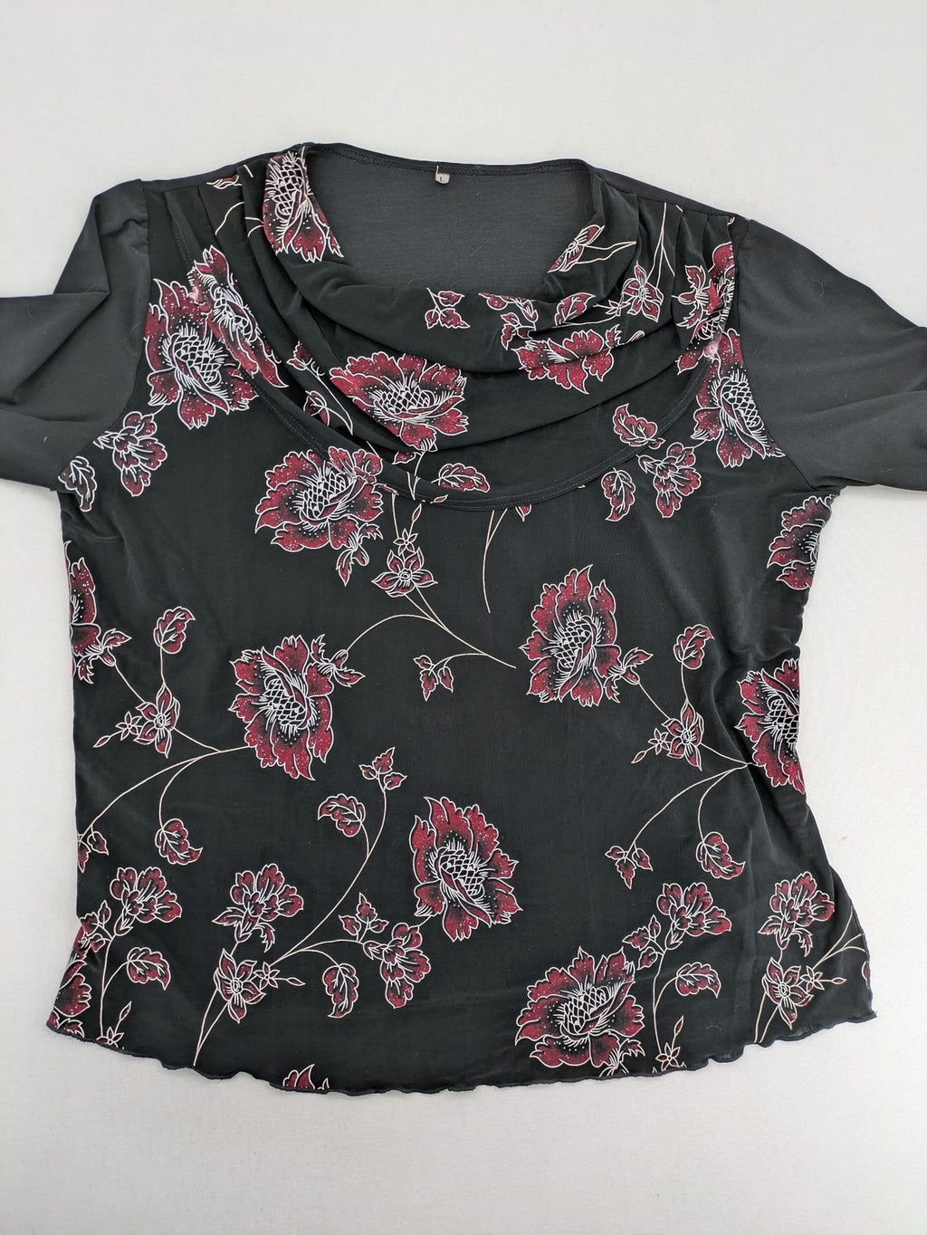 Damen black top with burgundy and white floral print, waterfall collar, and ruffled sleeves.