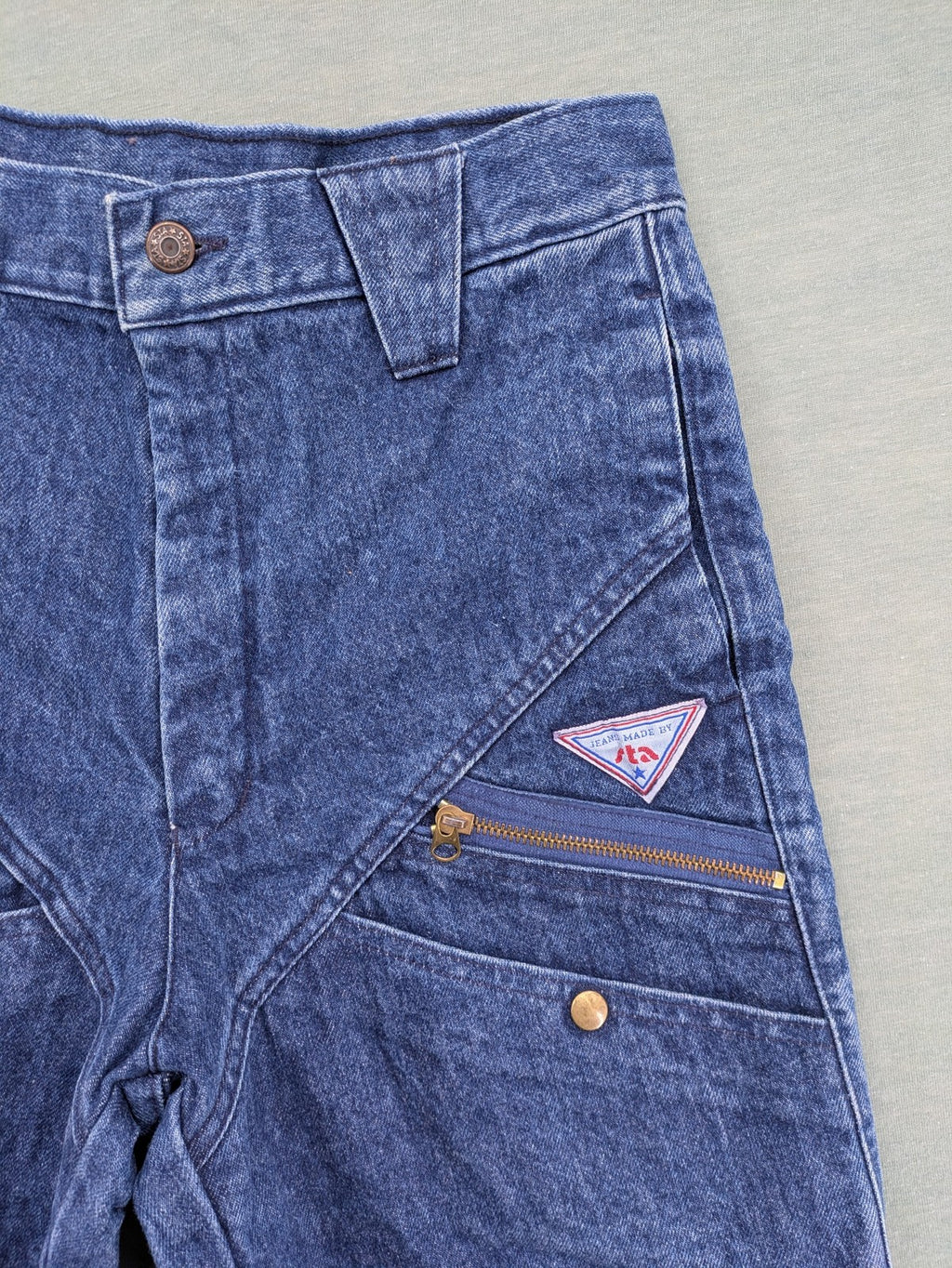 YKK blue high waist mom jeans with decorative front zipper pockets and vintage denim texture.