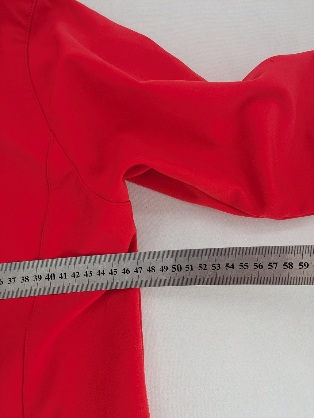 Pinea red softshell jacket with adjustable hood and fleece lining, multiple zippered pockets.