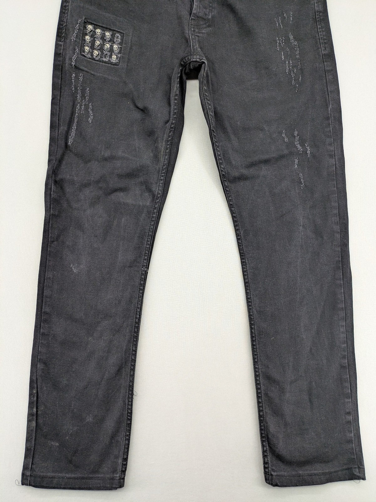 Philipp Plein black straight jeans with distressed finish and skull patch detail.