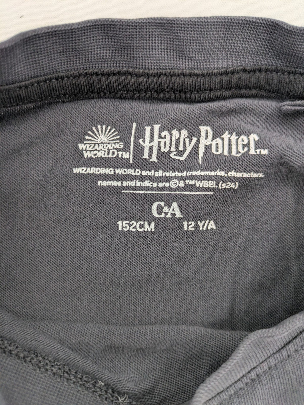 Harry Potter blue t-shirt featuring colorful Hogwarts crest and "I'd Rather Be At Hogwarts" slogan.
