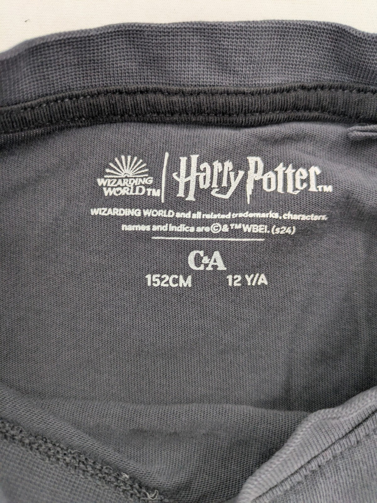 Harry Potter blue t-shirt featuring colorful Hogwarts crest and "I'd Rather Be At Hogwarts" slogan.