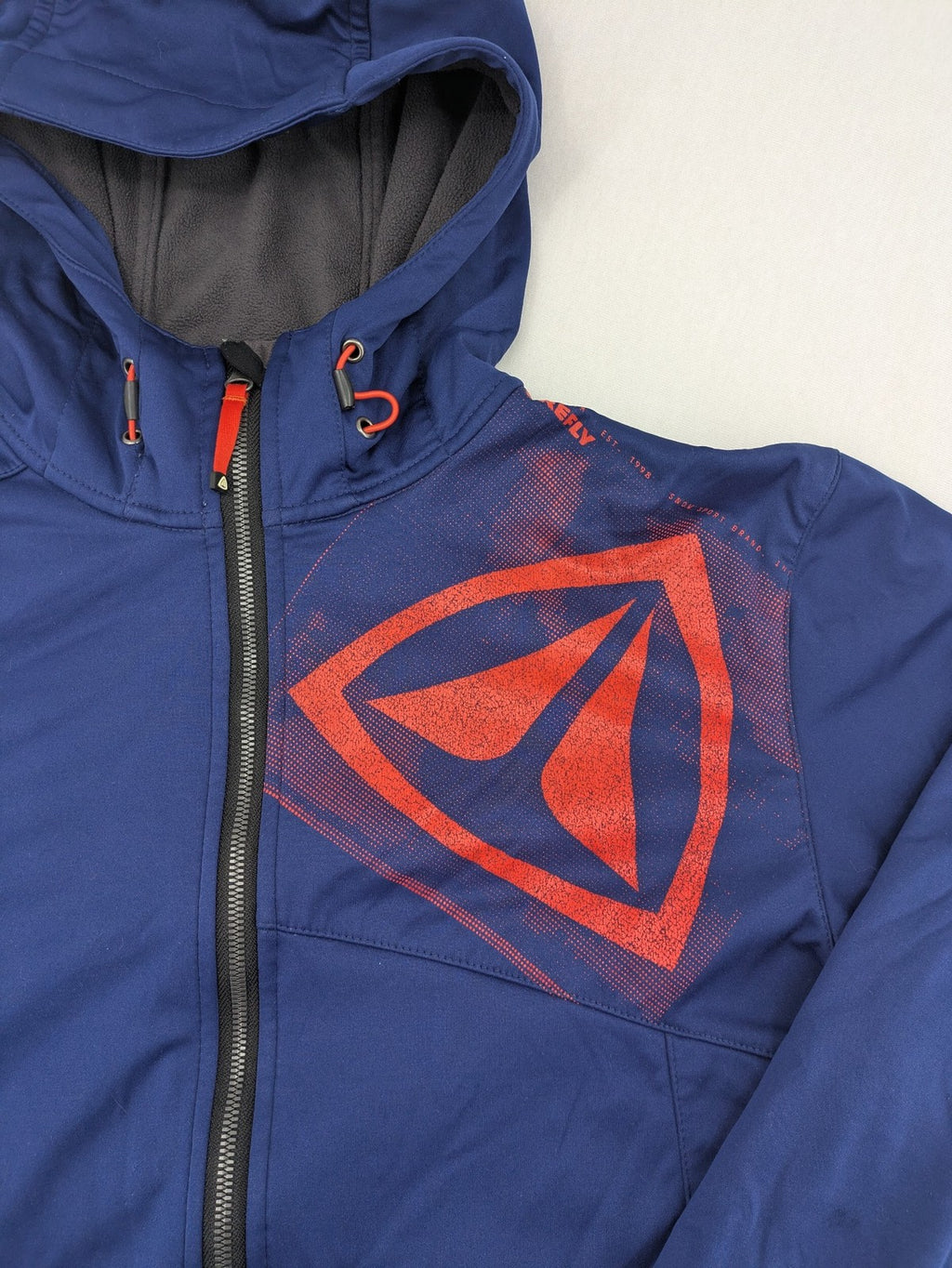 Firefly blue softshell jacket with adjustable hood and prominent chest logo.