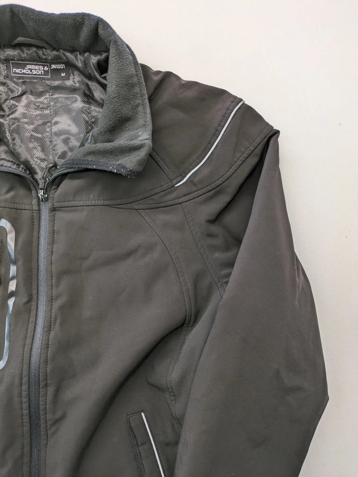 James & Nicholson grey softshell jacket with fleece lining and multiple zip pockets.