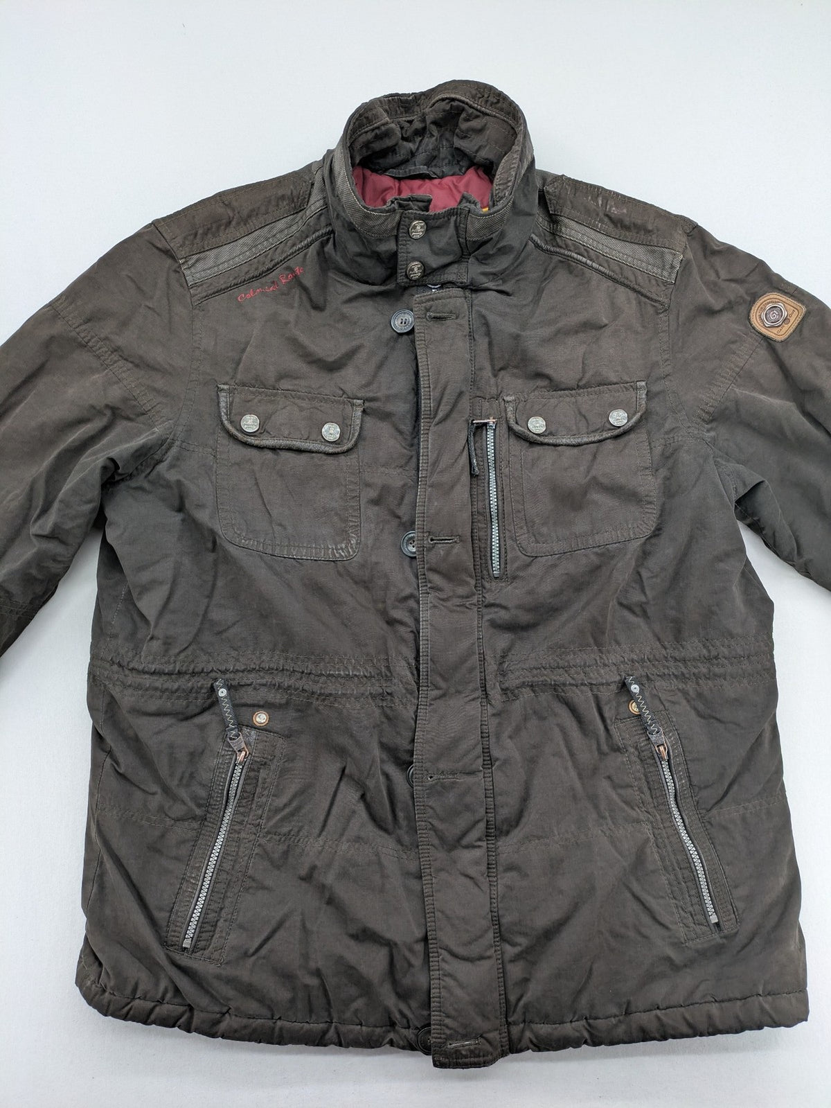 Gate One brown field jacket with plaid lining, multiple pockets, and zip-button closure.