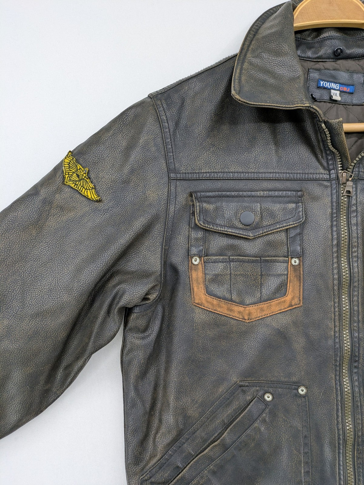 Junge brown bomber jacket with vintage patches and embroidered details in faux leather.