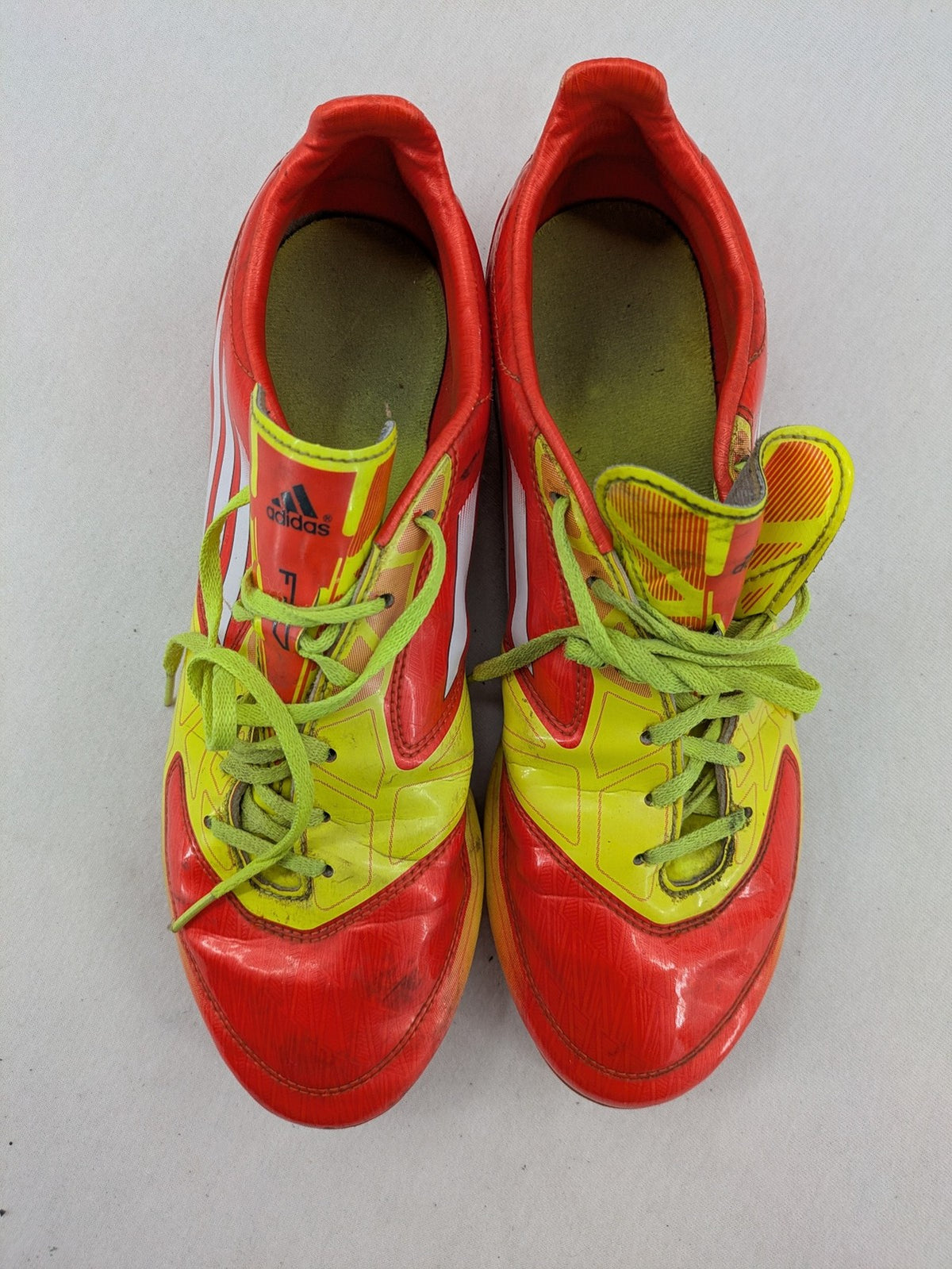 Adidas F50 soccer shoes red and yellow with three-stripe logo and lightweight synthetic material.