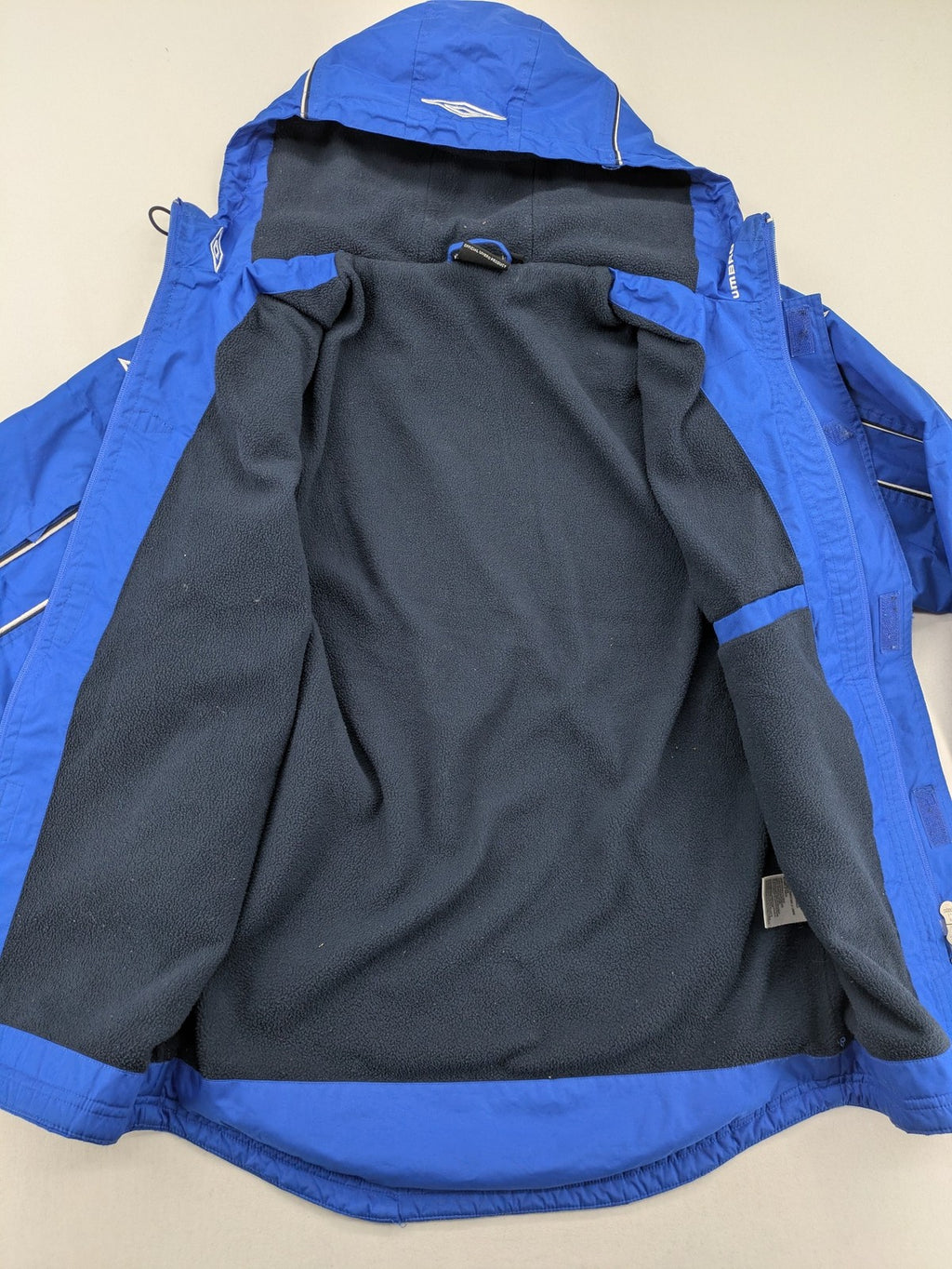 Umbro blue fleece-lined jacket with hood, reflective details, and white piping.