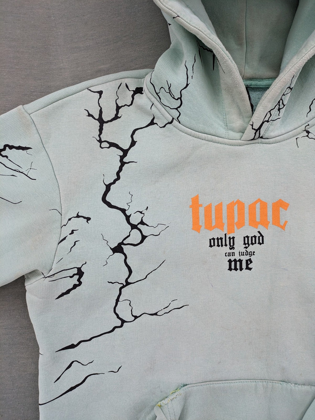 Tupac black and green zip-through hoodie with "Only God Can Judge Me" front print and angel wings graphic.