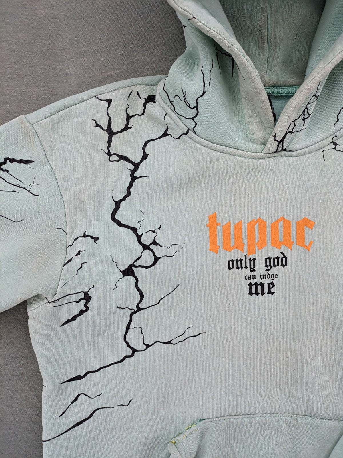 Tupac black and green zip-through hoodie with "Only God Can Judge Me" front print and angel wings graphic.