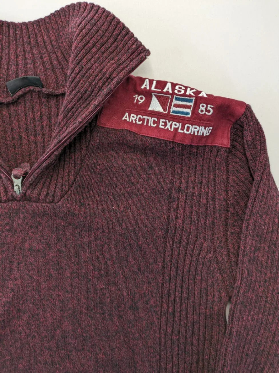 Infinity burgundy turtle neck jumper with quarter-zip and ribbed knit texture.