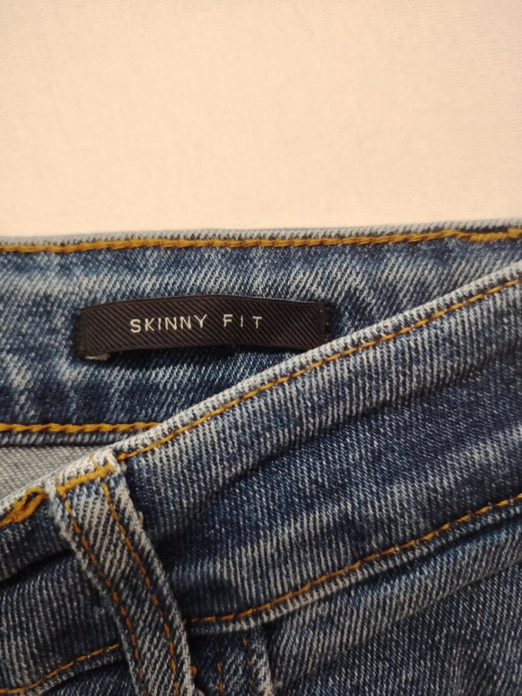 Damen blue skinny jeans with ripped details, five-pocket style, and classic button closure.