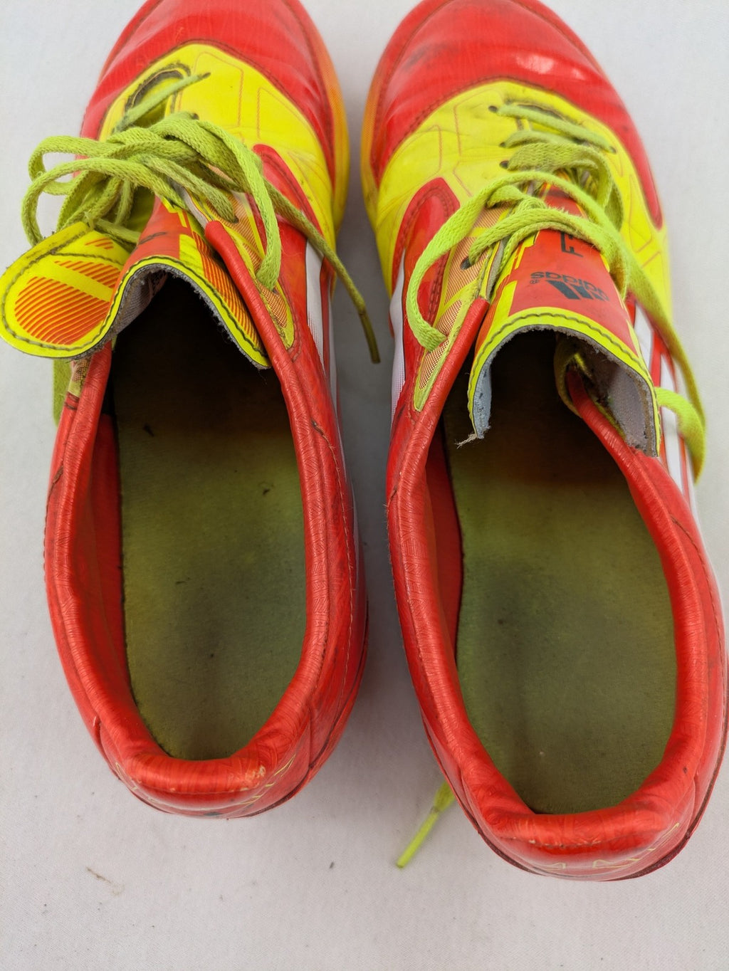 Adidas F50 soccer shoes red and yellow with three-stripe logo and lightweight synthetic material.