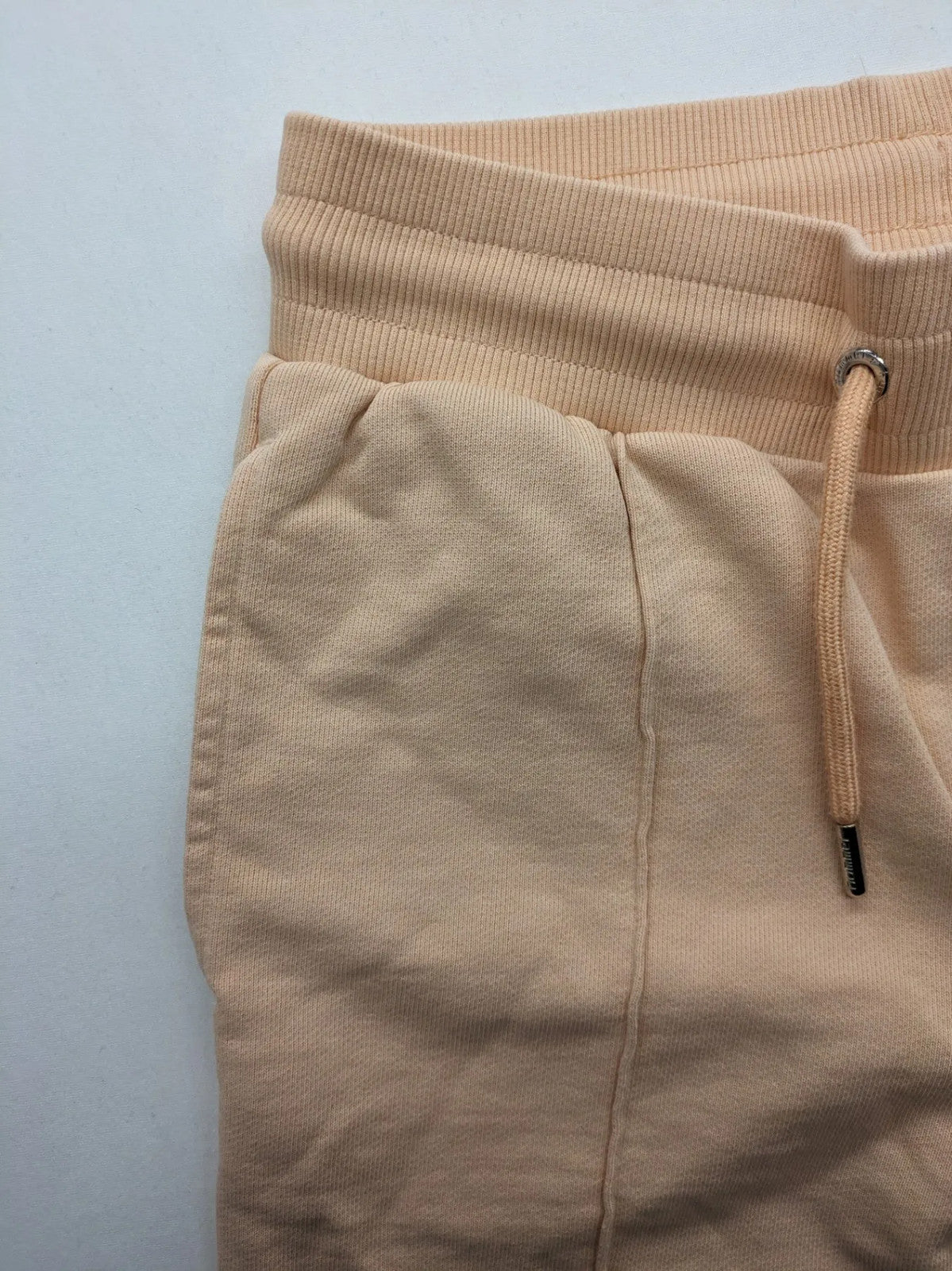 Hummel beige jogging pants with adjustable drawstring, embroidered logo, and ankle cuffs.