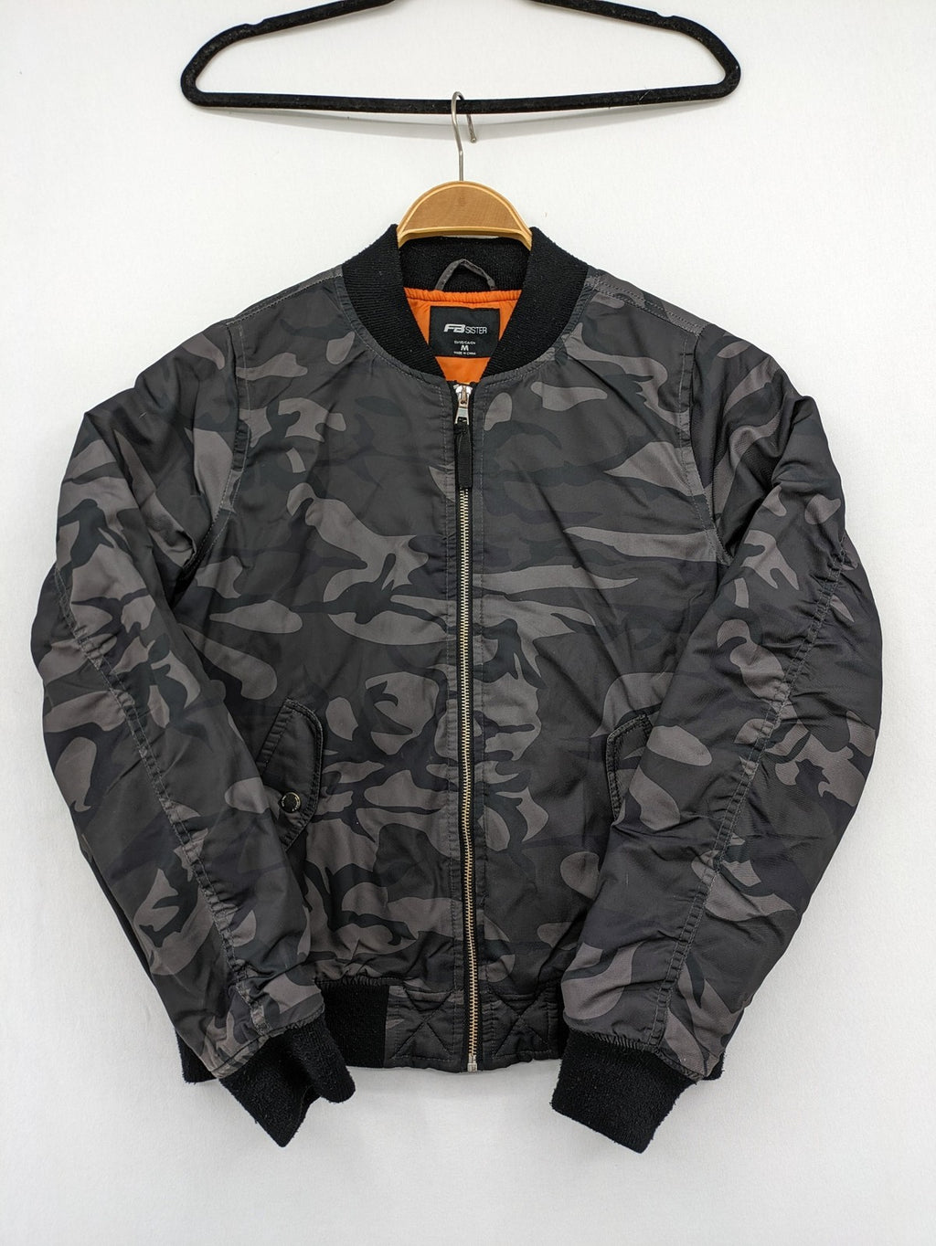 FB Sister orange bomber jacket with gray camouflage pattern and quilted lining.