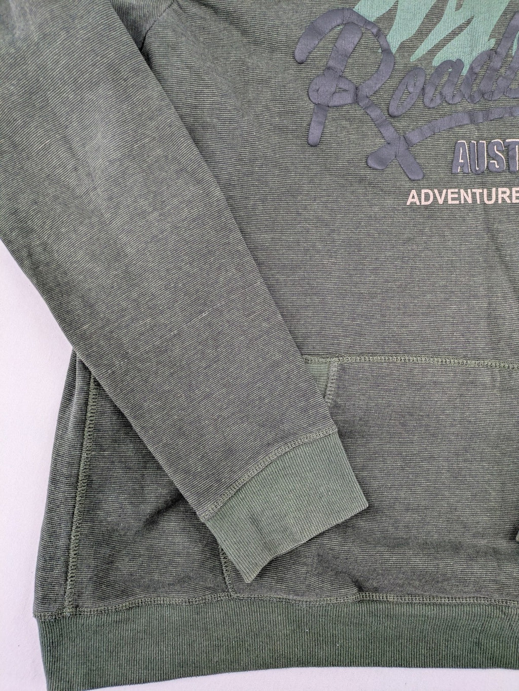 Roadsign Australia green hoodie with mountain graphic print and logo patch on sleeve.