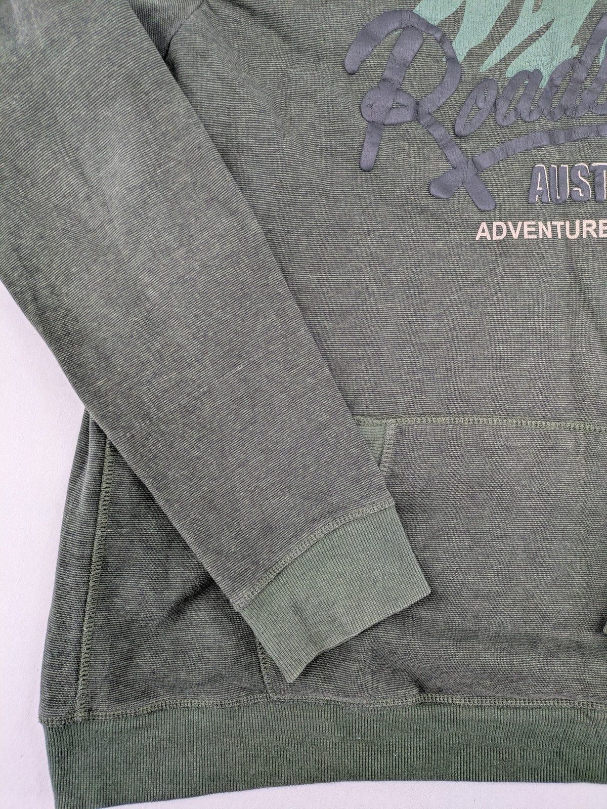 Roadsign Australia green hoodie with mountain graphic print and logo patch on sleeve.