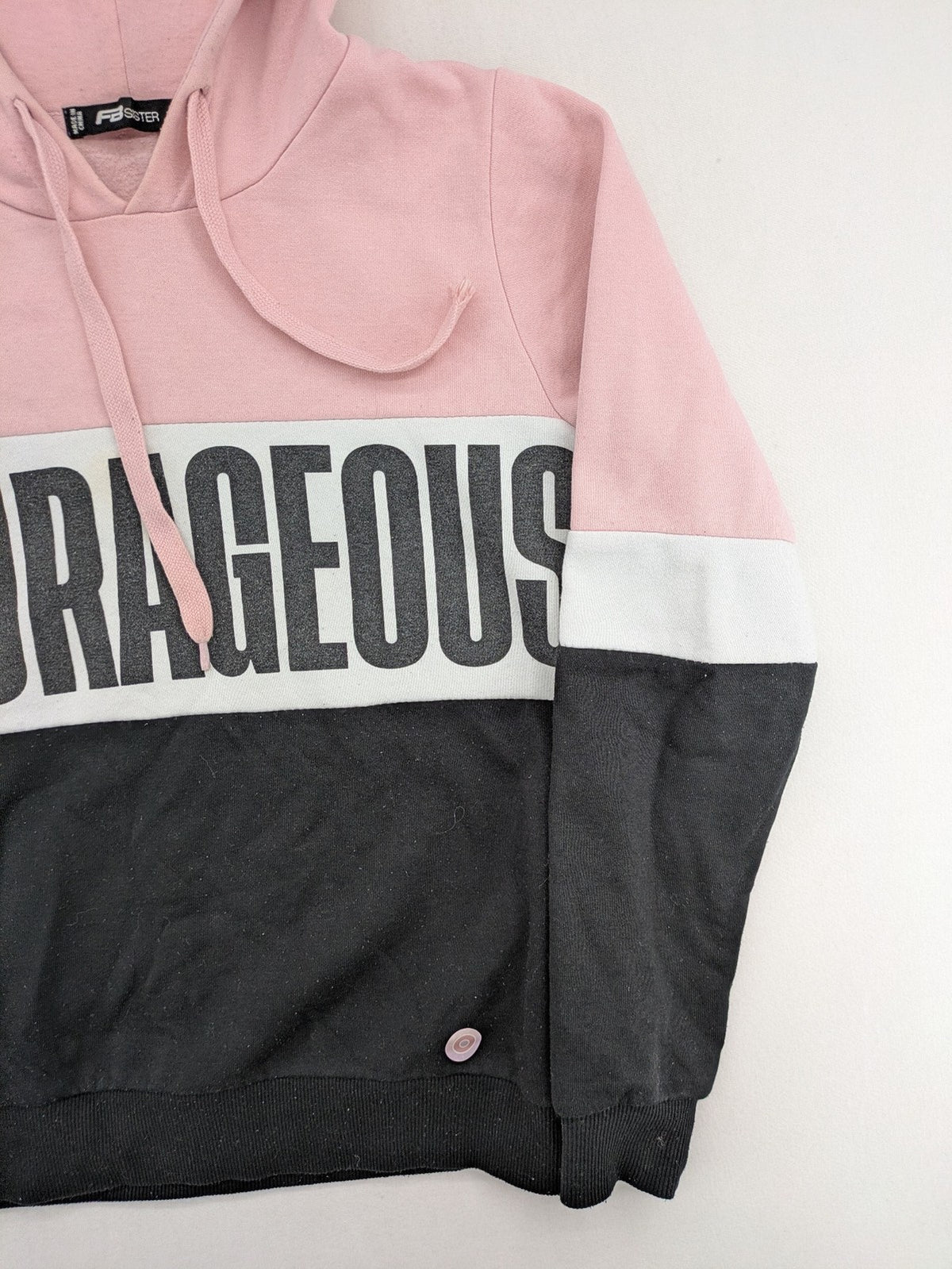 FB Sister multi hoodie colorblock design pink, white, black with "COURAGEOUS" graphic print.
