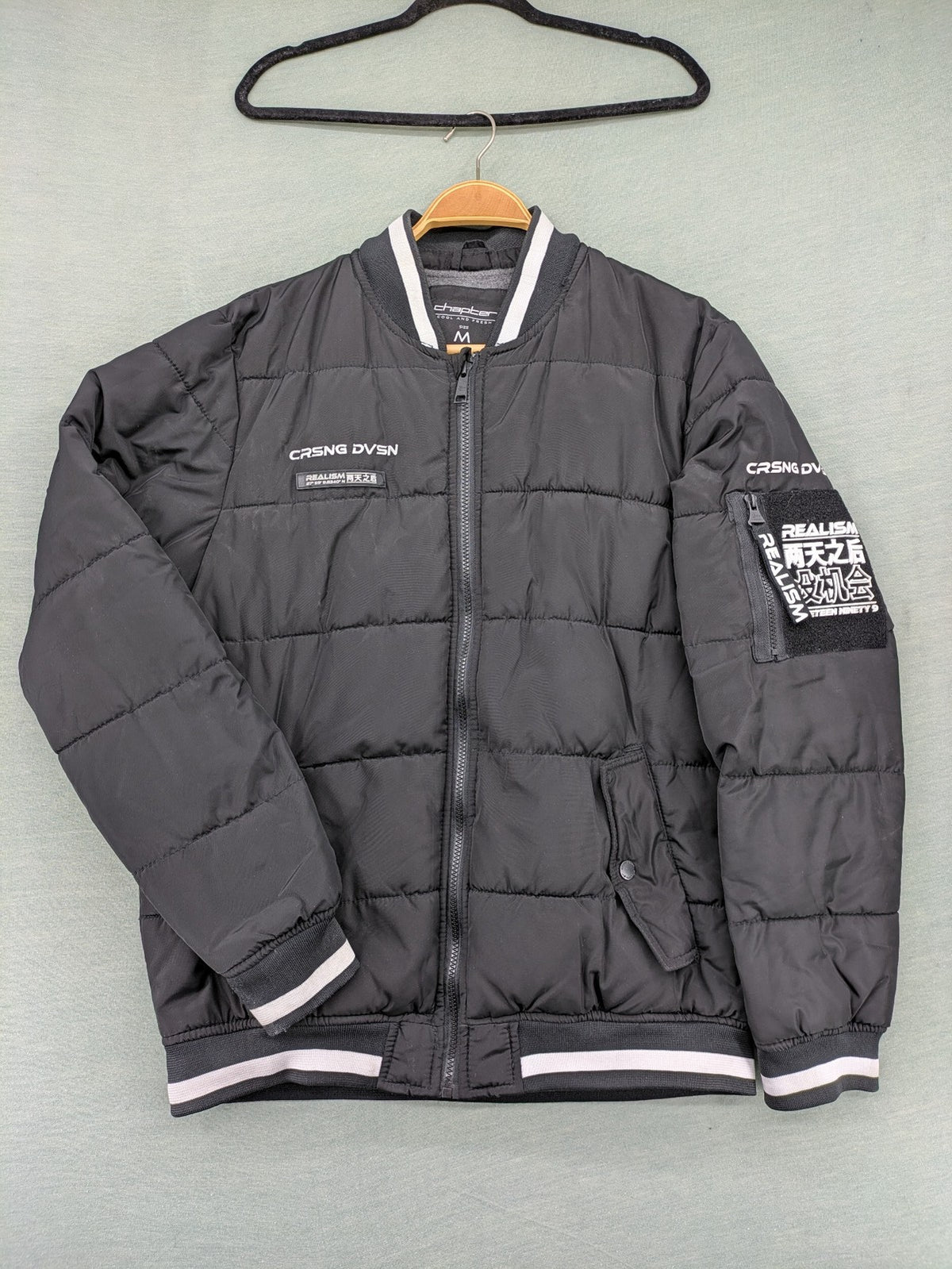 Chapter black bomber jacket with patches, striped ribbed cuffs, and full zip closure.