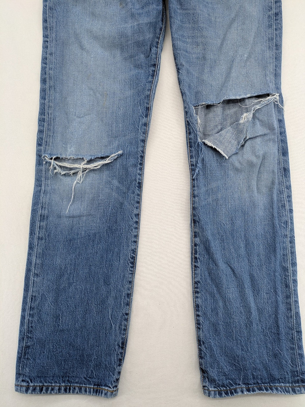 Levi's blue straight jeans with button-fly and distressed knee rips.