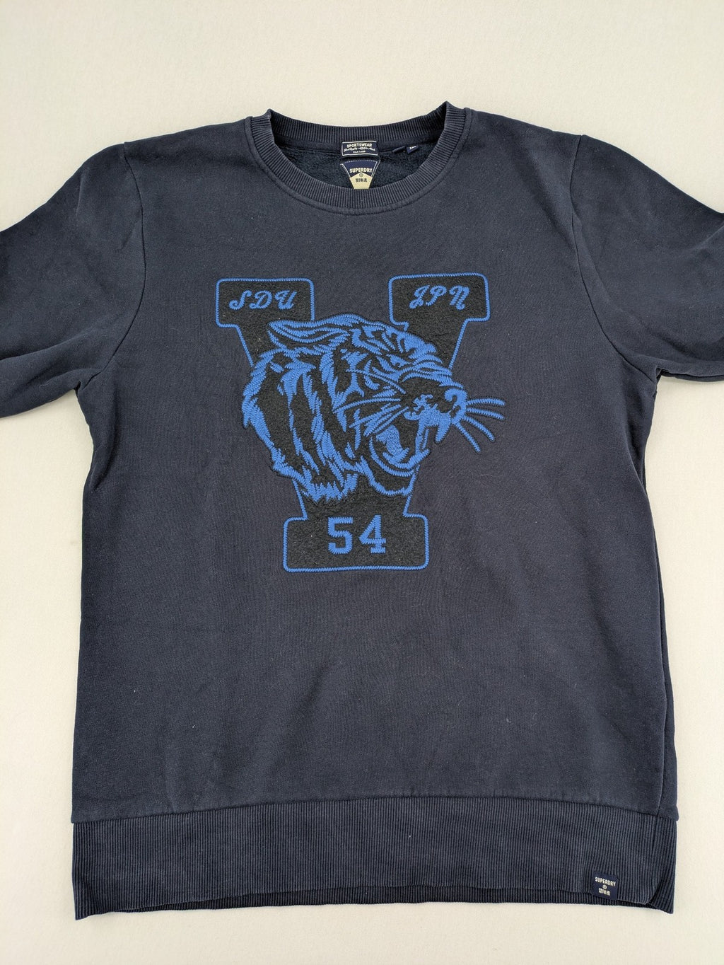 Superdry navy sweatshirt with embroidered tiger graphic and "JPN 54" chenille detail.