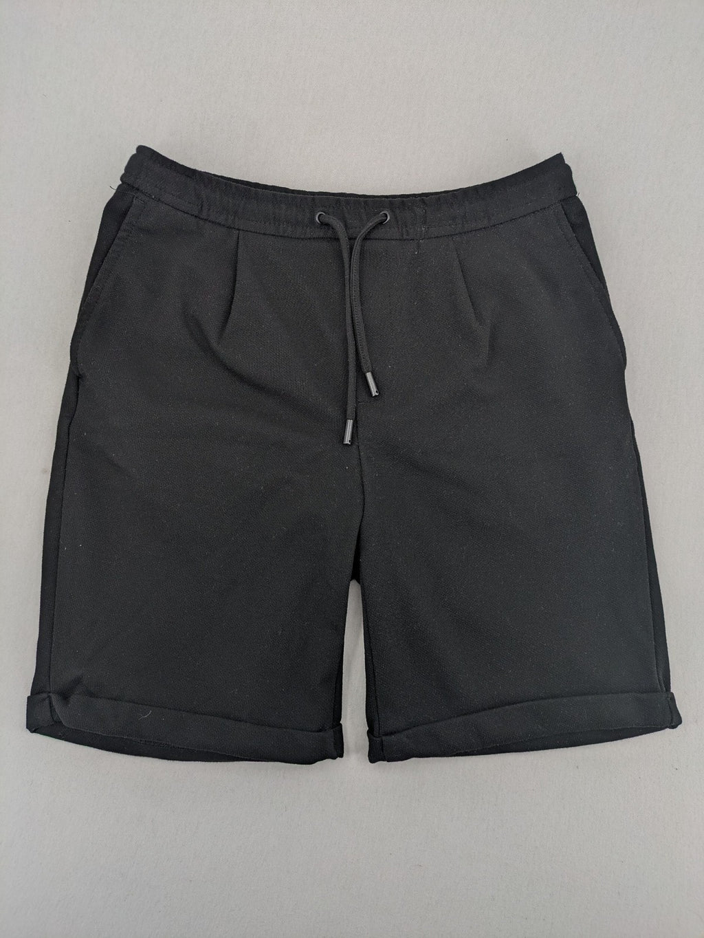 Zara black shorts with elastic drawstring, pleats, and rolled hem detail.