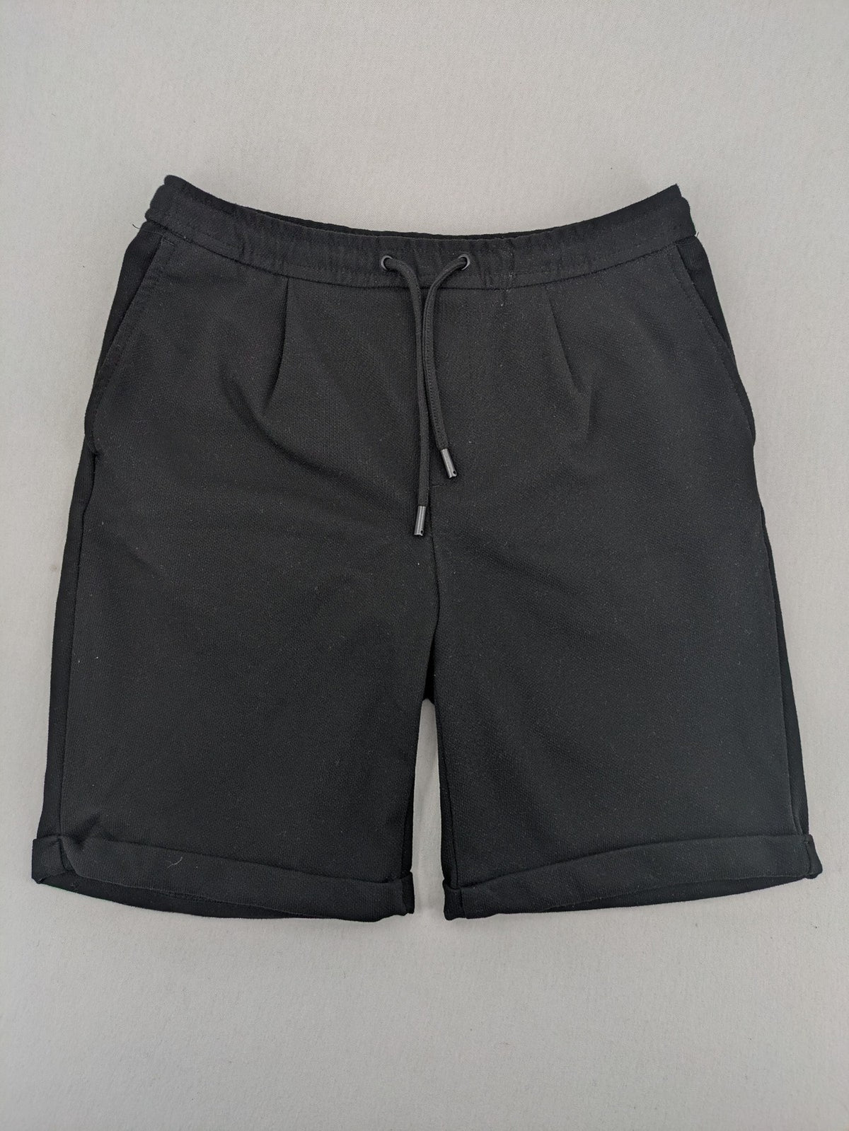 Zara black shorts with elastic drawstring, pleats, and rolled hem detail.
