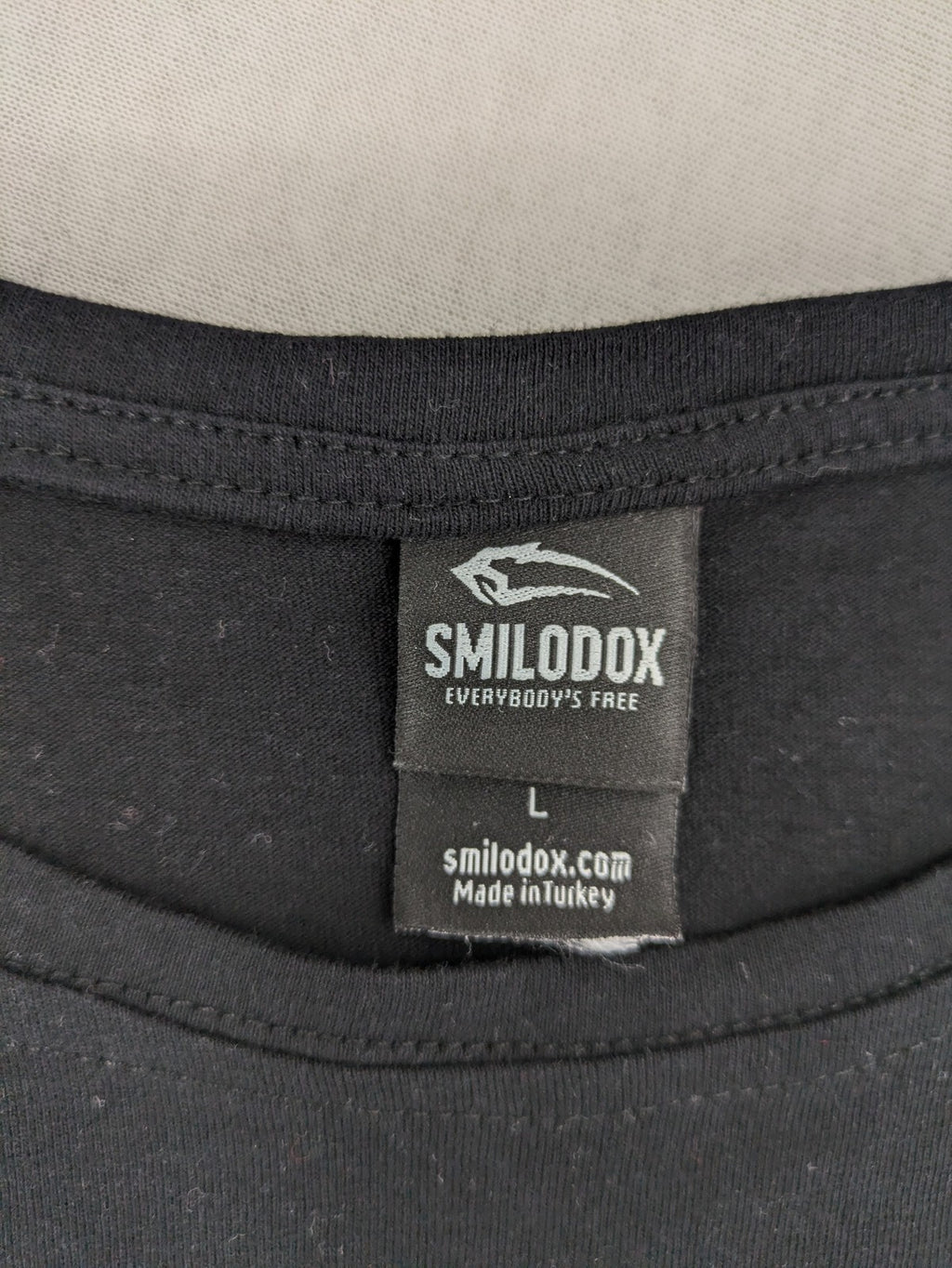 Smilodox black T-shirt minimalist design with subtle brand patch, 100% cotton.