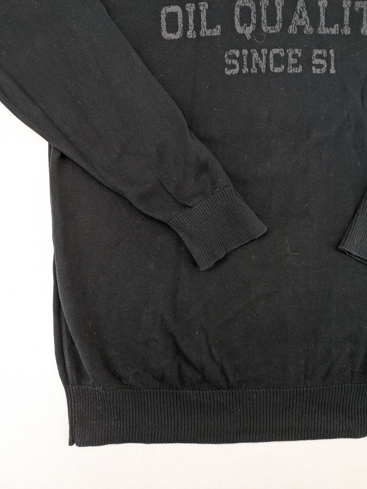 Angelo Litrico black knit jumper V-neck with tonal emblem and "Supreme Oil Quality" graphic.