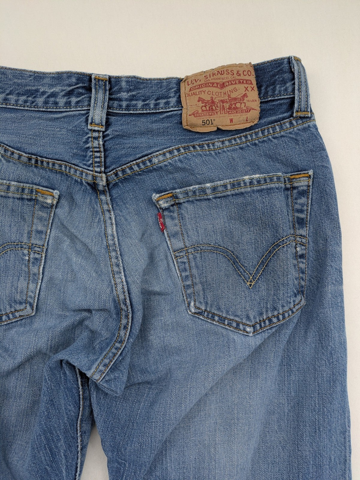 Levi's blue straight jeans with button-fly and distressed knee rips.