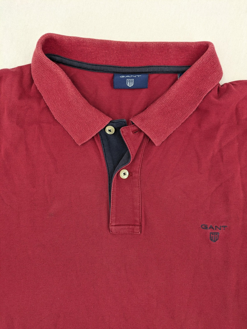 GANT burgundy polo shirt with embroidered shield logo and contrasting navy collar details.