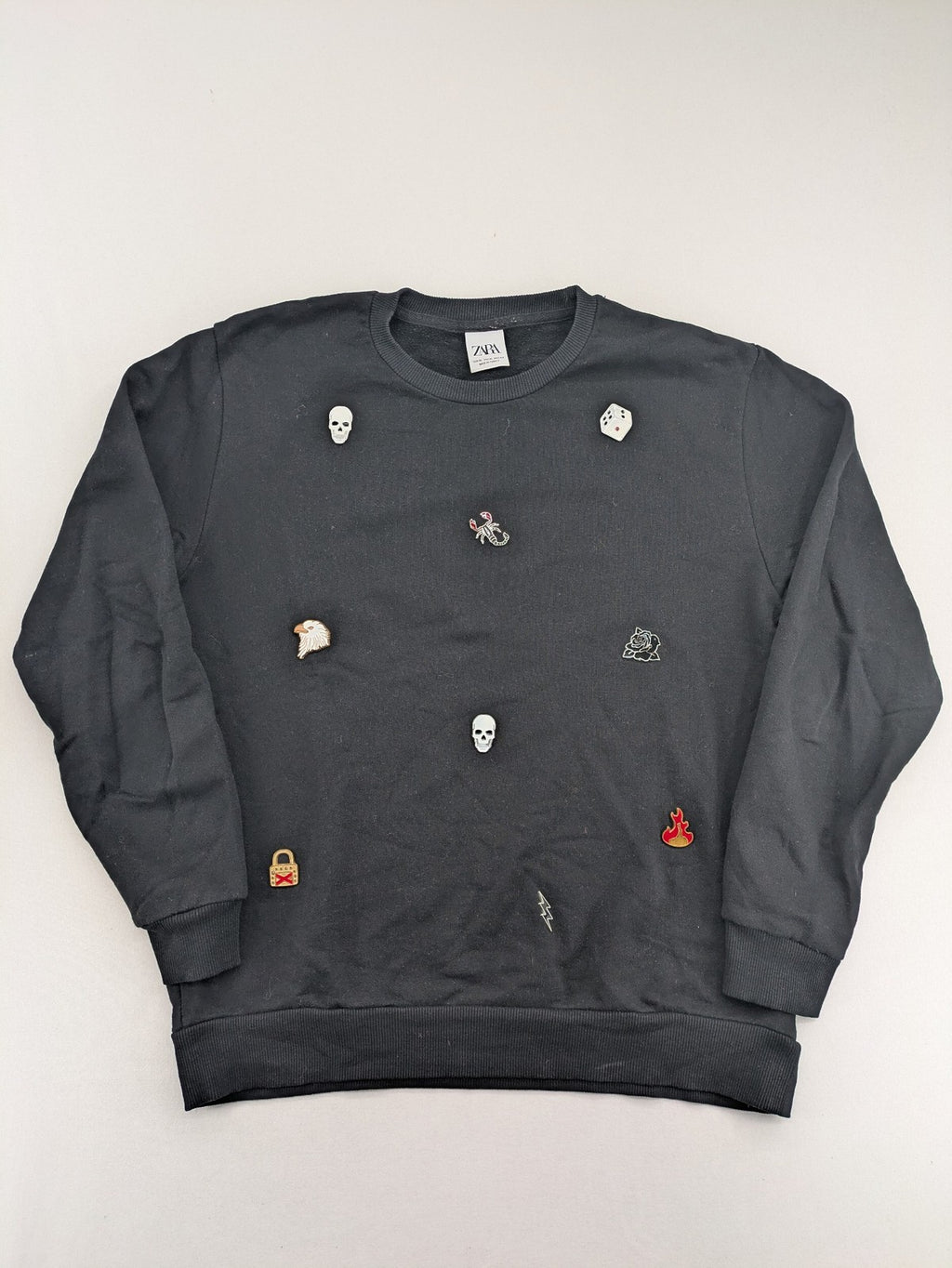 Zara grey turtle neck jumper with skull, scorpion, flame, and eagle embellishments.