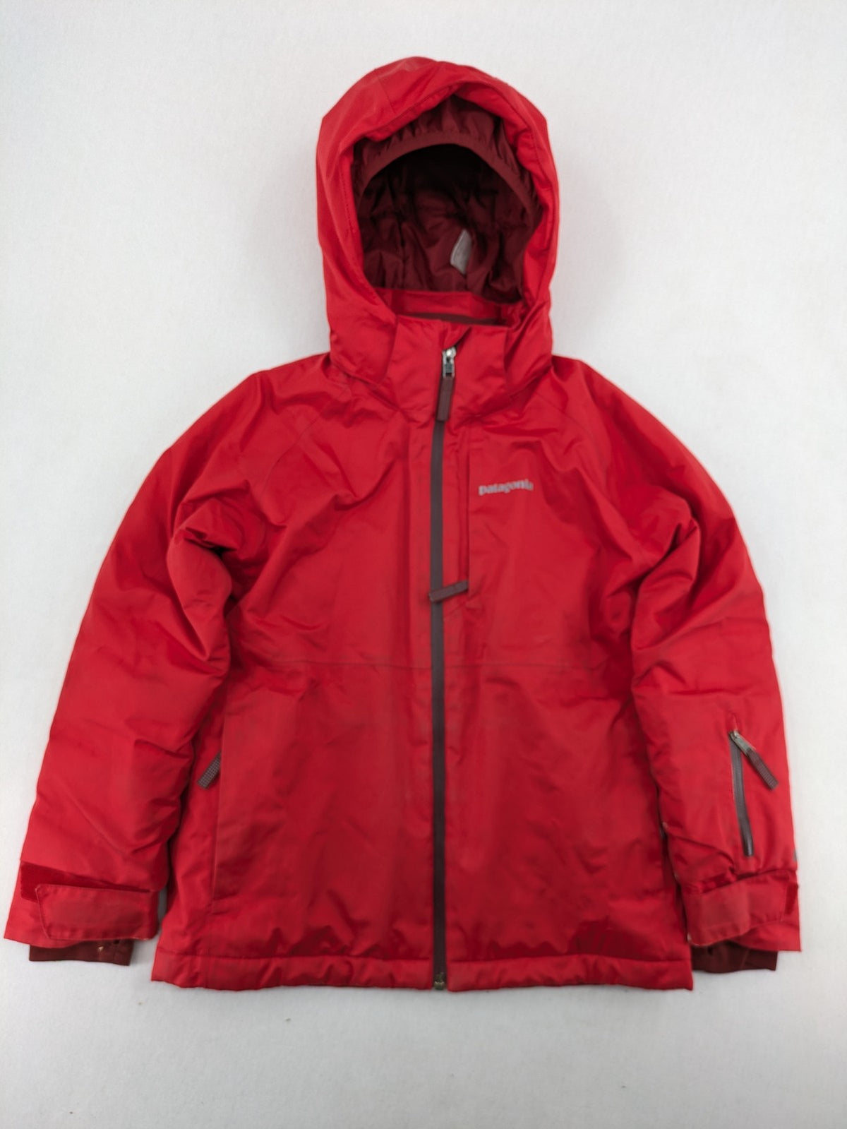 Patagonia red winter coat with hood, zip closure, snow skirt, and ski pass pocket.