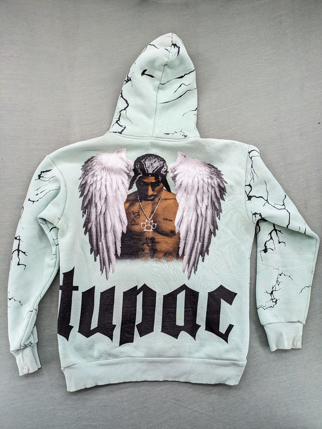 Tupac black and green zip-through hoodie with "Only God Can Judge Me" front print and angel wings graphic.