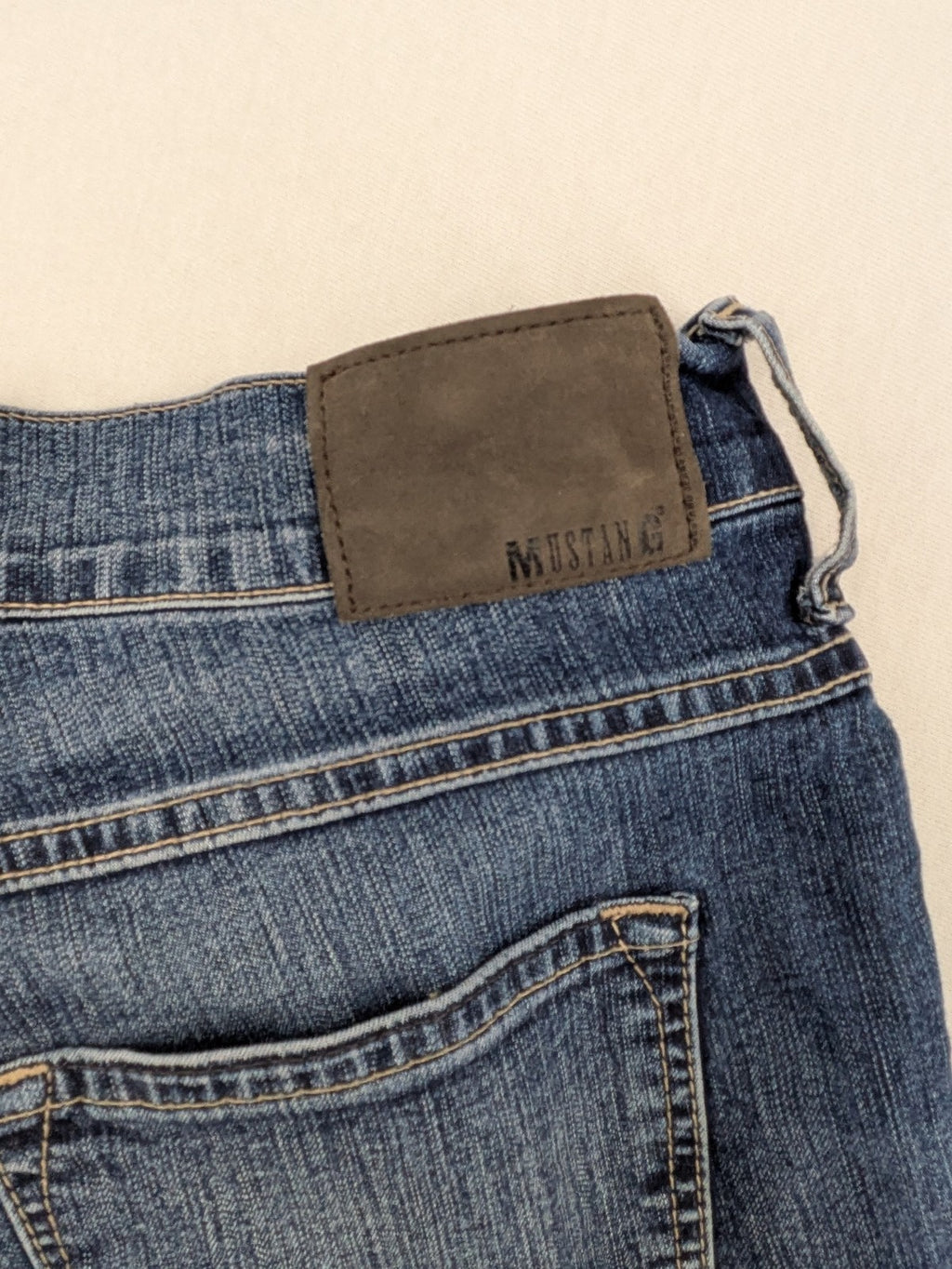 Mustang blue bootcut jeans with custom painted floral designs on both legs.