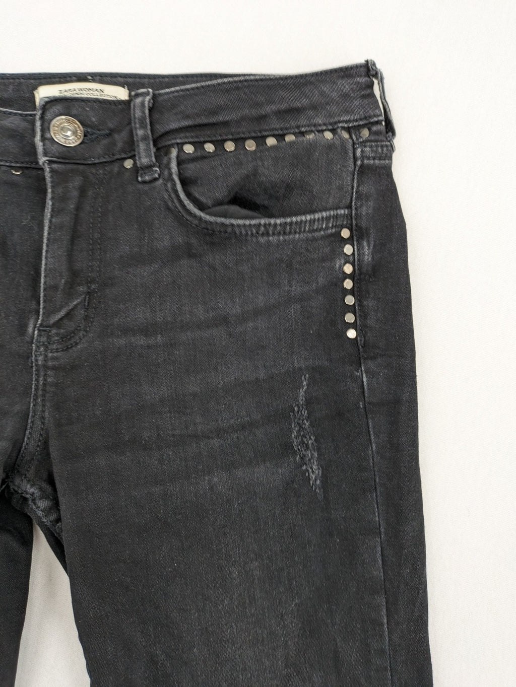 Zara Woman black skinny jeans with distressed details, silver studs, and frayed hem.